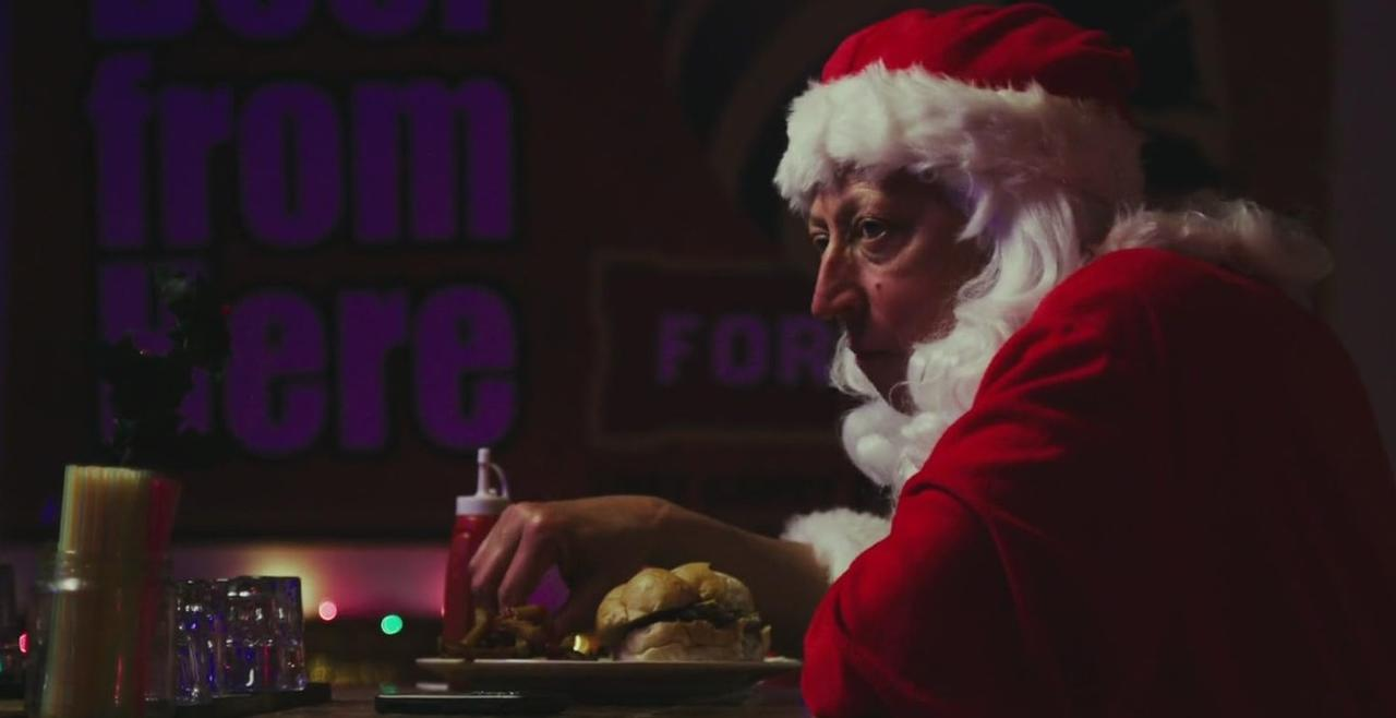 Ein Mann im Weihnachtsmannkostüm isst einen Burger und Pommes.