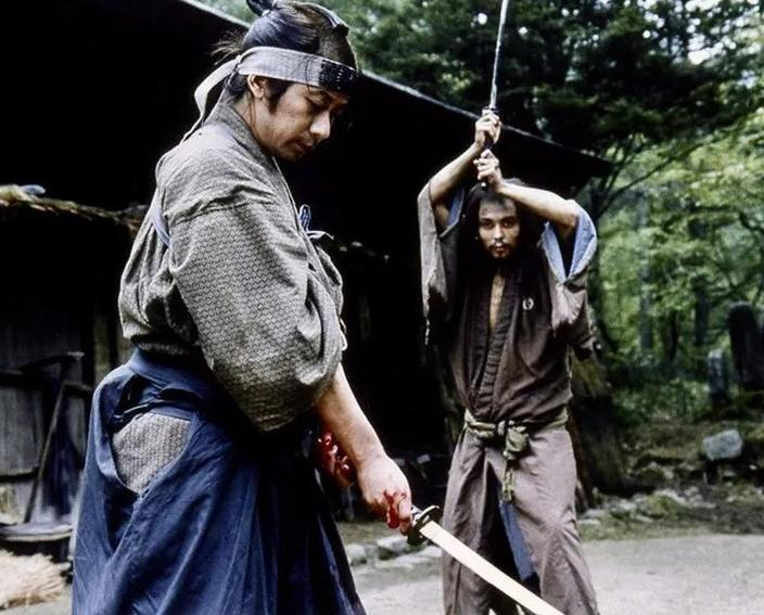 Zwei Samurai in traditioneller Kleidung mit Schwertern, einer blickt nach unten.
