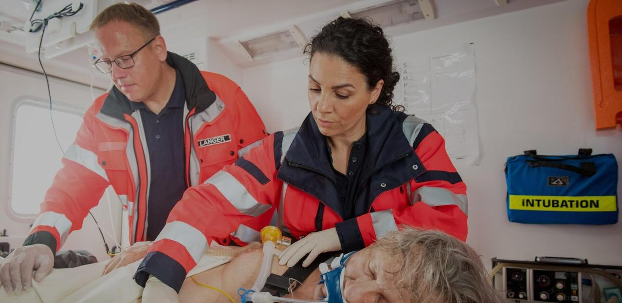 Rettungssanitäter behandeln Patienten in einem Krankenwagen. Ein blauer Beutel mit 