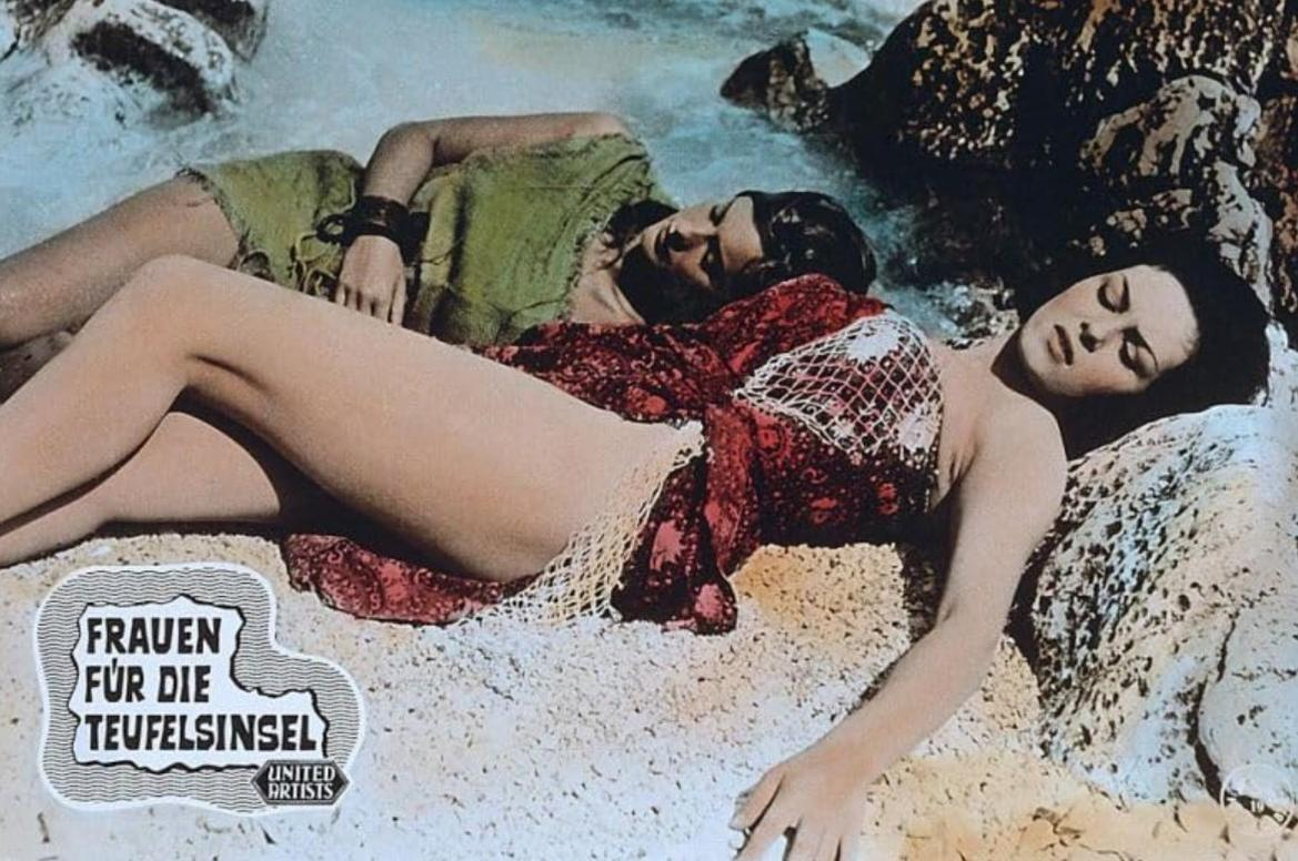 Zwei Frauen liegen am Strand. Eine trägt ein grünes Kleid, die andere ein rotes Tuch.