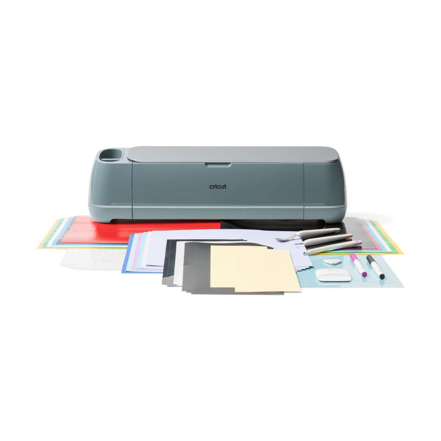 Una macchina Cricut grigia con materiali per crafting come carta e penne.