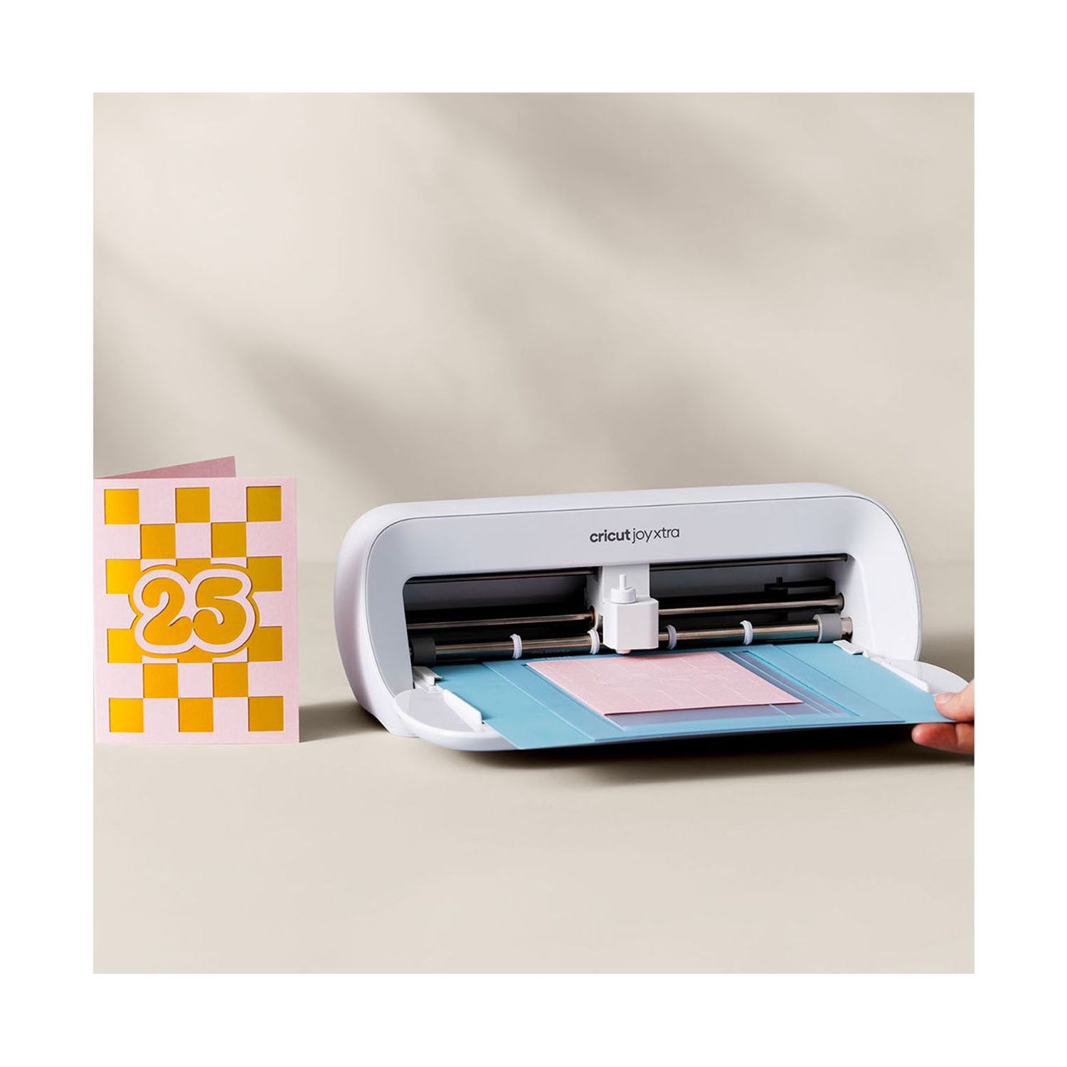 Una macchina da taglio Cricut Joy Xtra bianca con un biglietto rosa a scacchi con il numero 25.