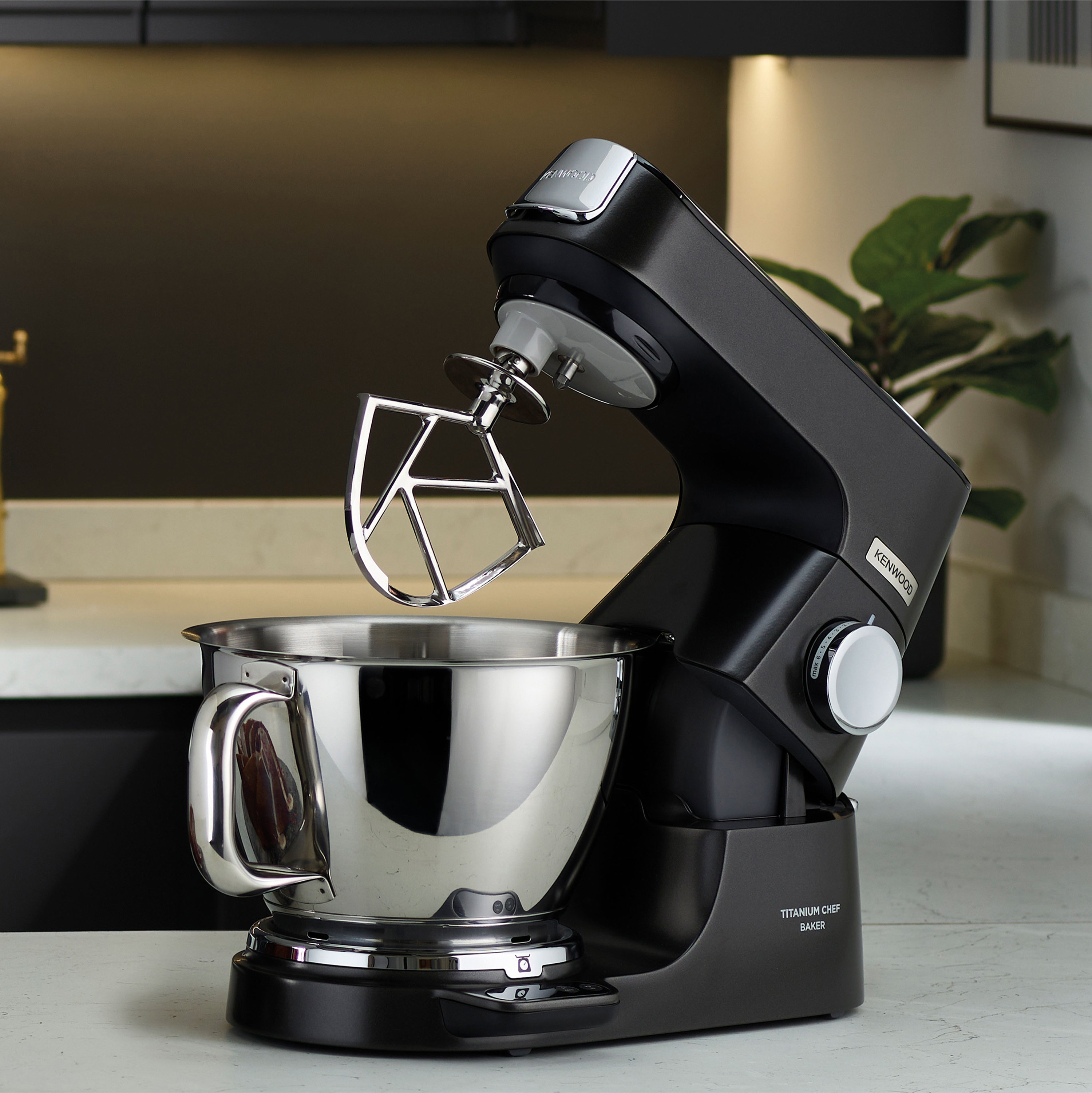 Ein dunkler Küchenmixer mit Edelstahlschüssel und Schneebesen.