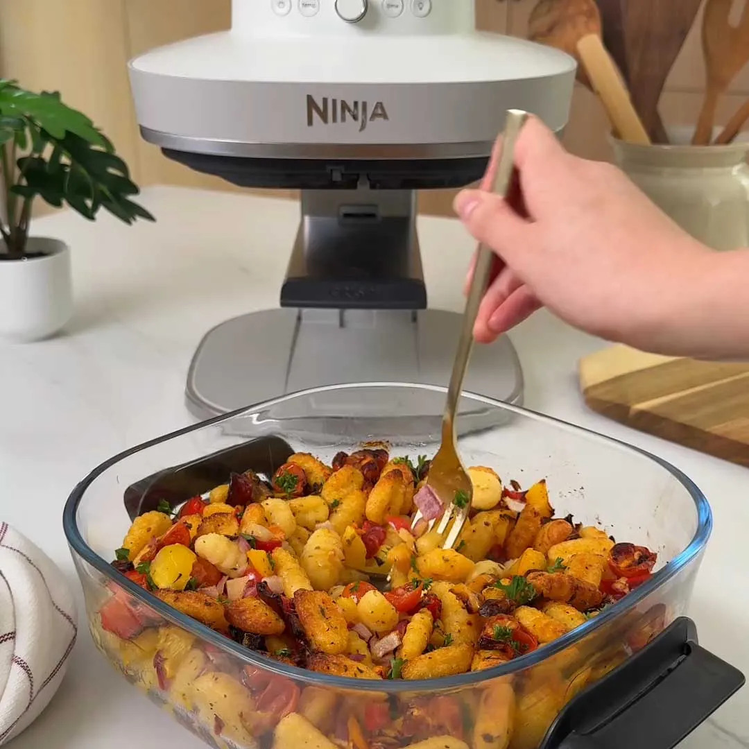 Pieczone gnocchi z warzywami w szklanej misce, obok urządzenia Ninja.
