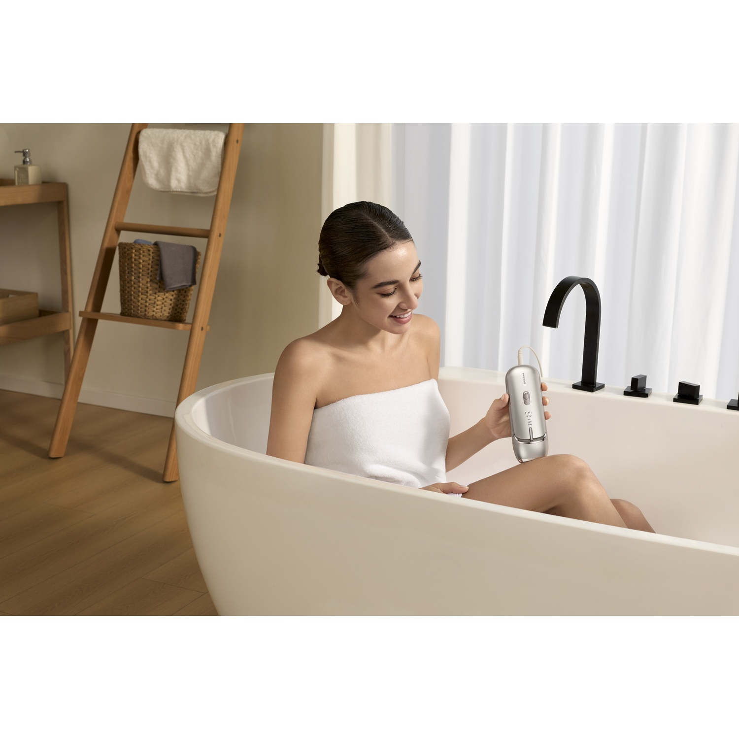 Une femme assise dans une baignoire tient un appareil argenté.