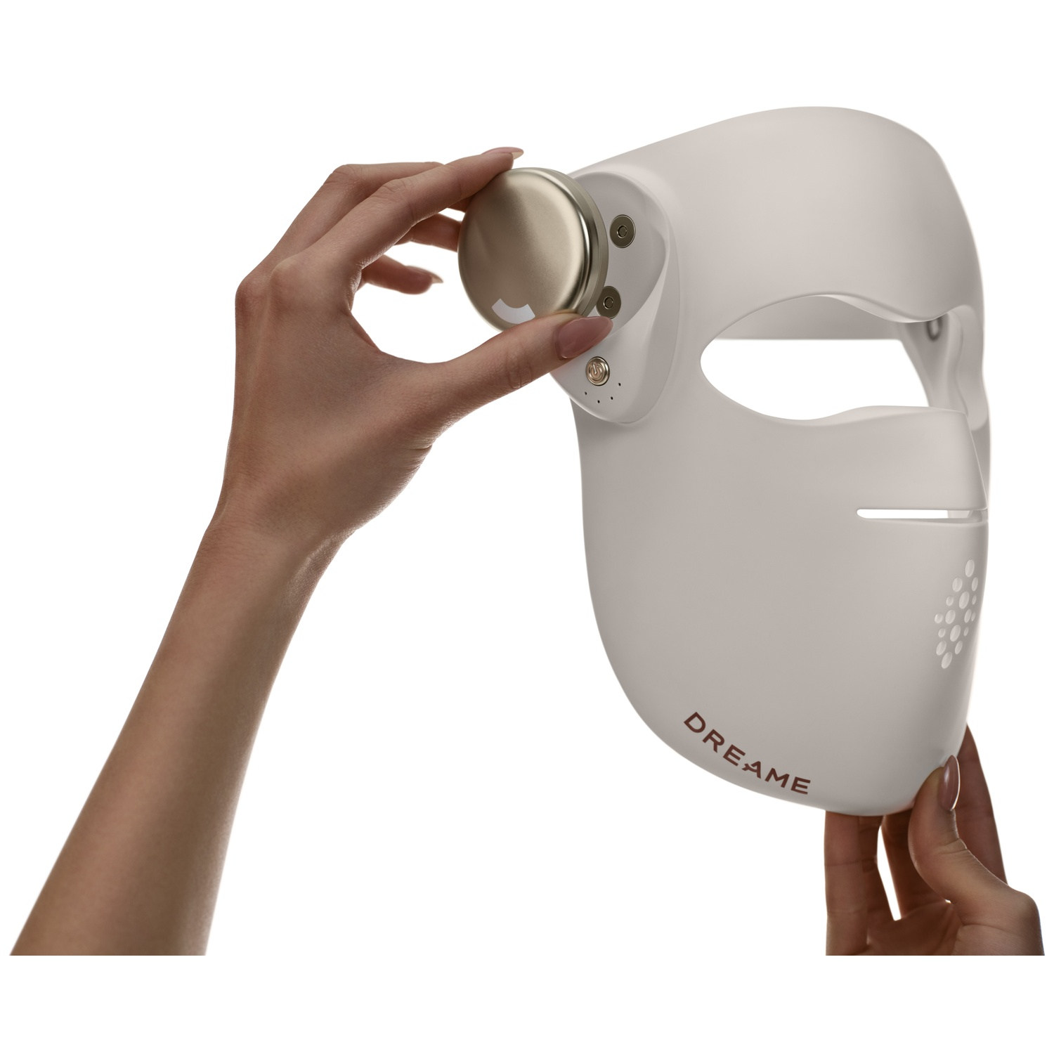 Une main tient un masque facial blanc avec le mot DREAME. Une autre main tient un bouton doré.