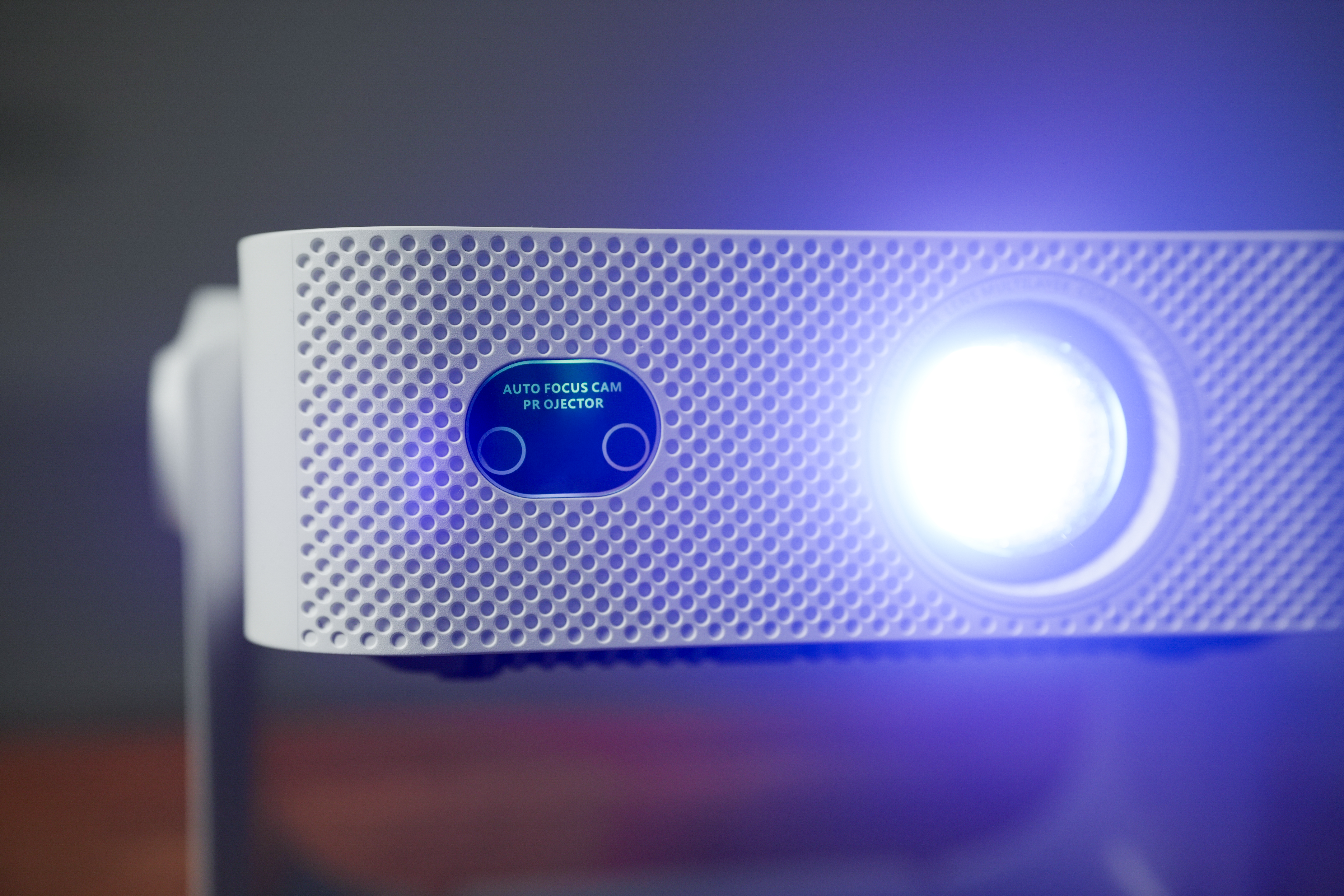 Ein weißer Projektor mit blauem Licht, der auf der linken Seite eine Lüftungsfläche hat.