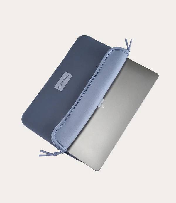 Un portátil gris se inserta parcialmente en una funda Tucano azul.