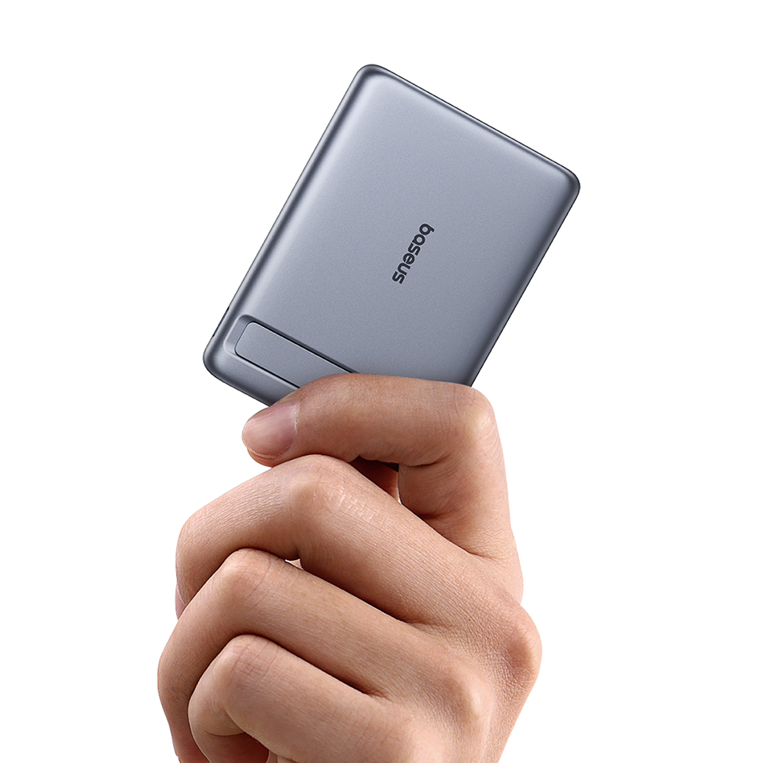 Una mano sujeta una unidad USB pequeña y gris con el logo "baseus".