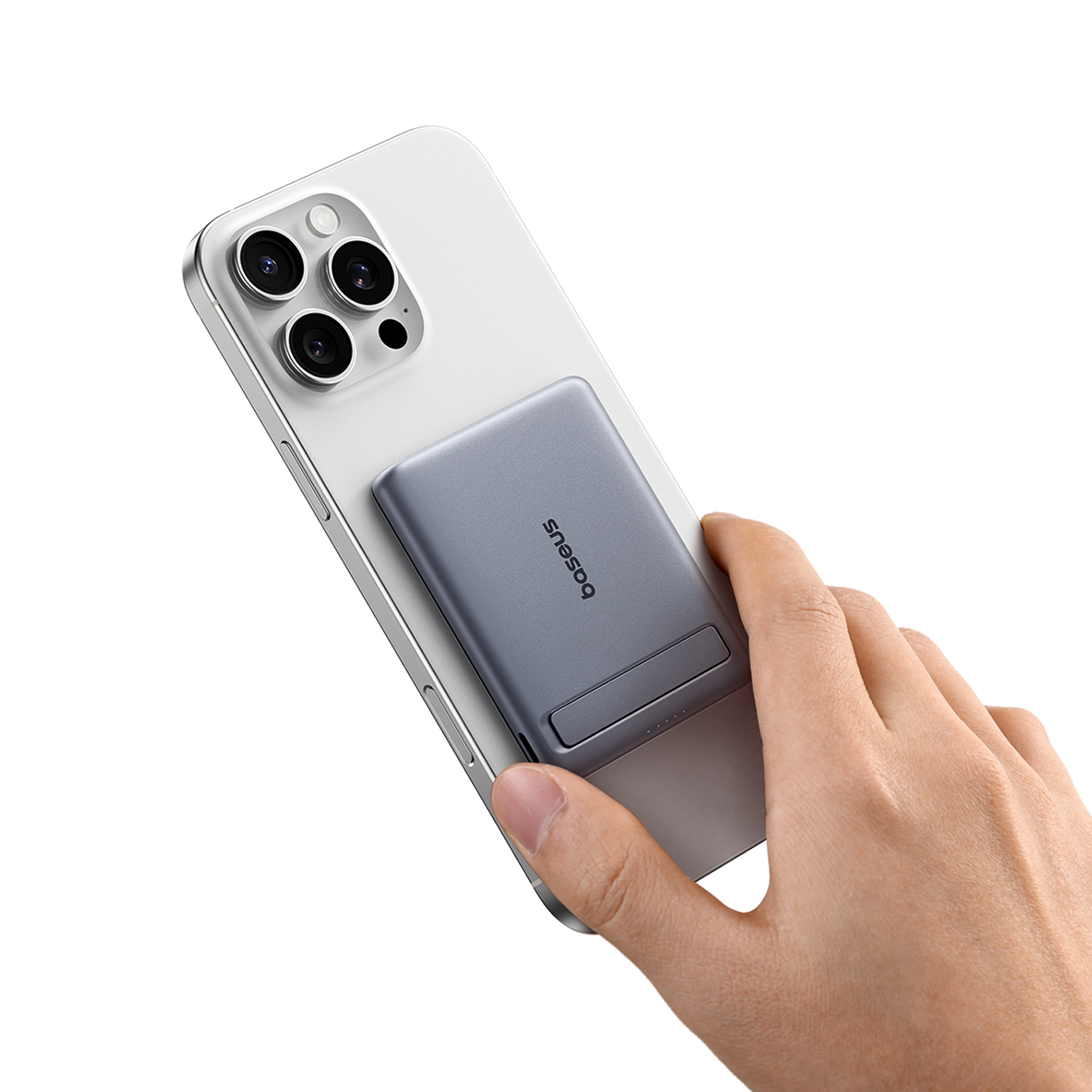 Una mano sujeta un teléfono gris con un cargador gris acoplado.