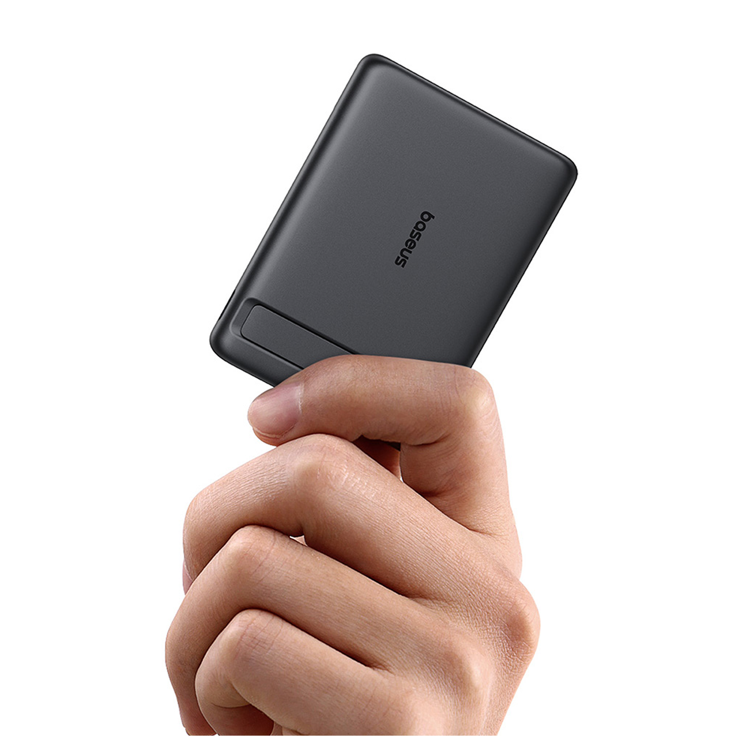 Una mano sostiene un pequeño dispositivo gris oscuro con el logo "Baseus".