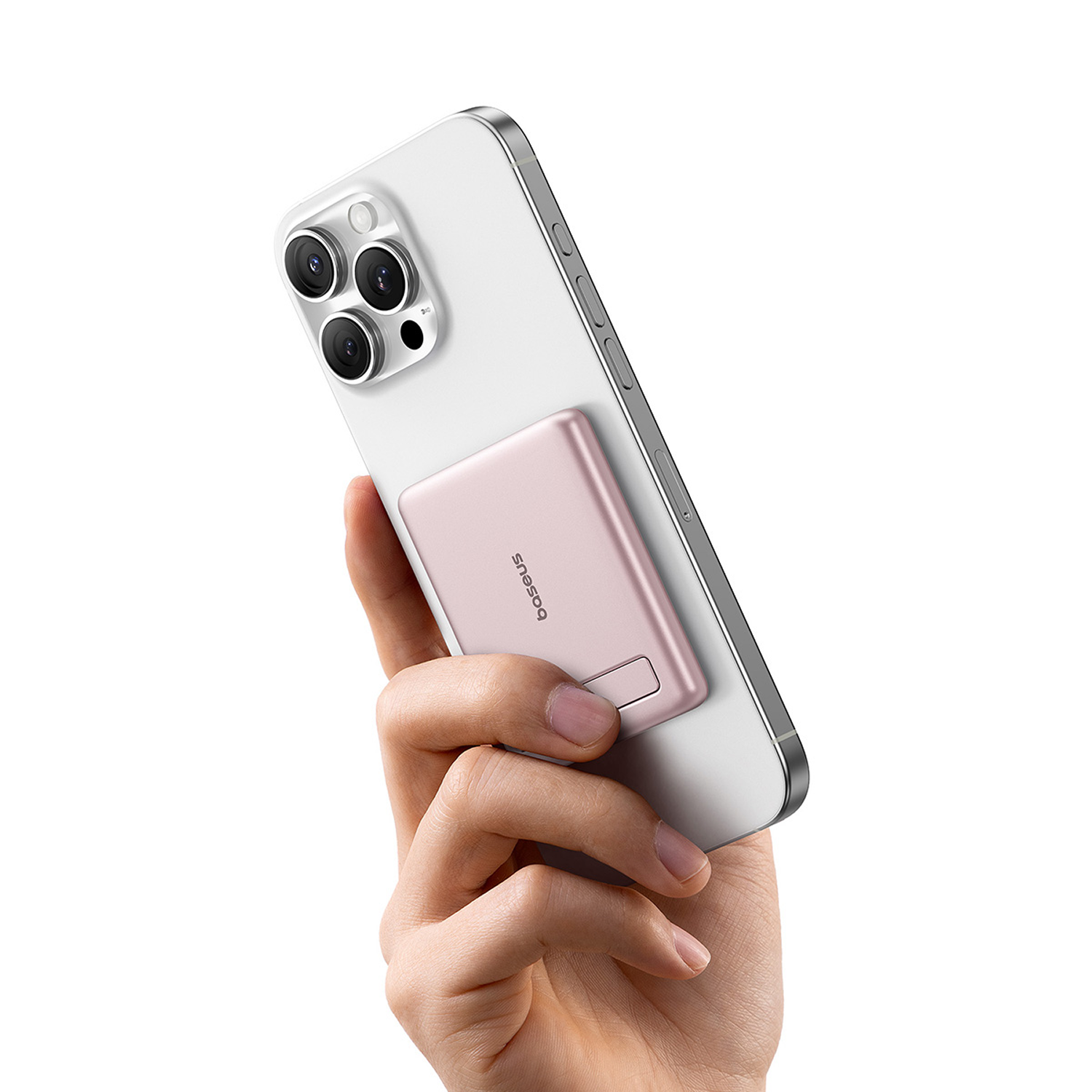 Una mano sostiene un smartphone blanco con una batería externa magnética rosa acoplada.