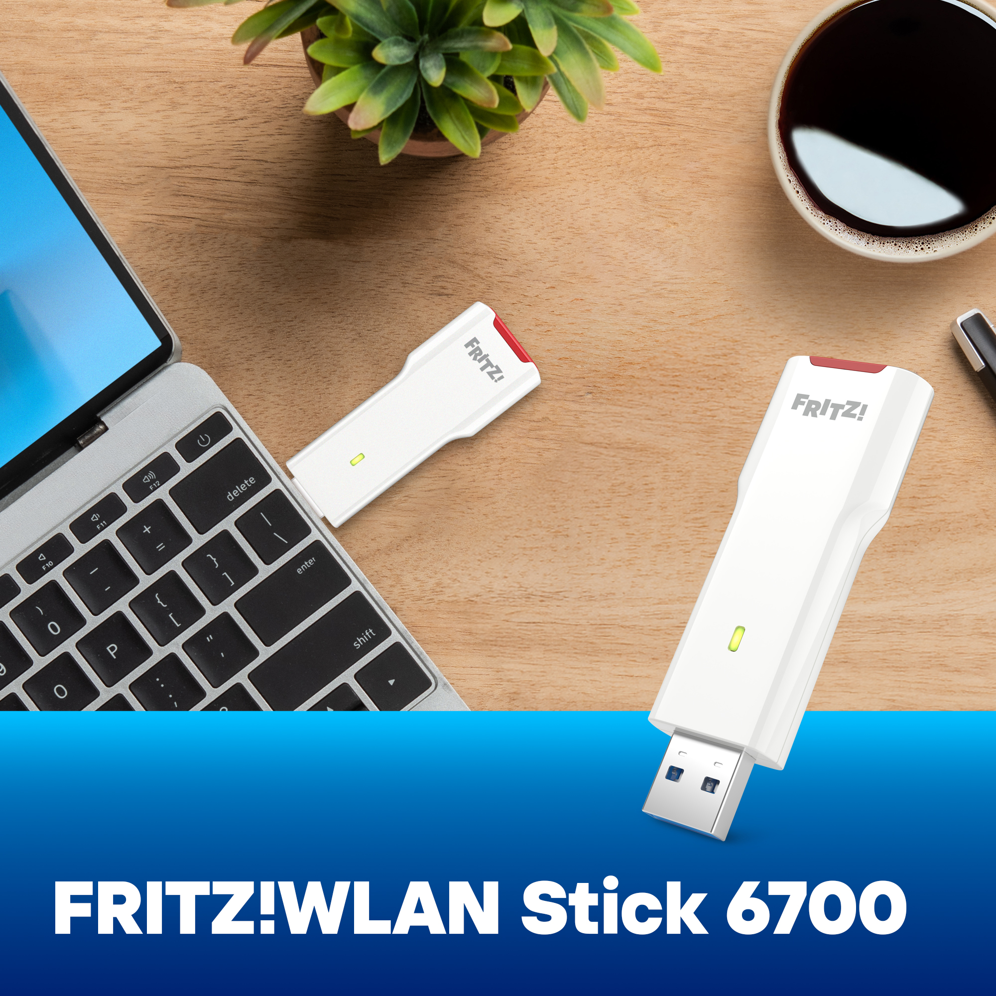 Zwei FRITZ!WLAN Sticks liegen auf einem Schreibtisch neben einem Laptop.