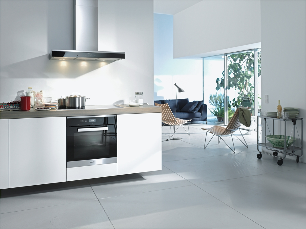Moderne Küche mit eingebautem Ofen und Wohnbereich mit Sofa und Stühlen.