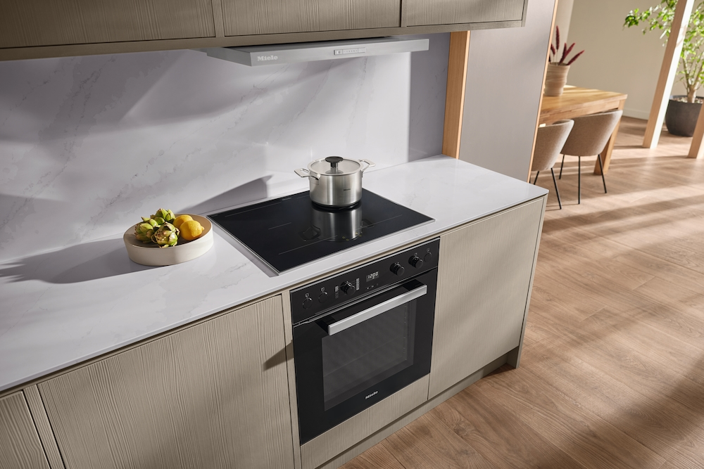 Moderne Küche mit Induktionskochfeld, Topf, Obstschale und Ofen.