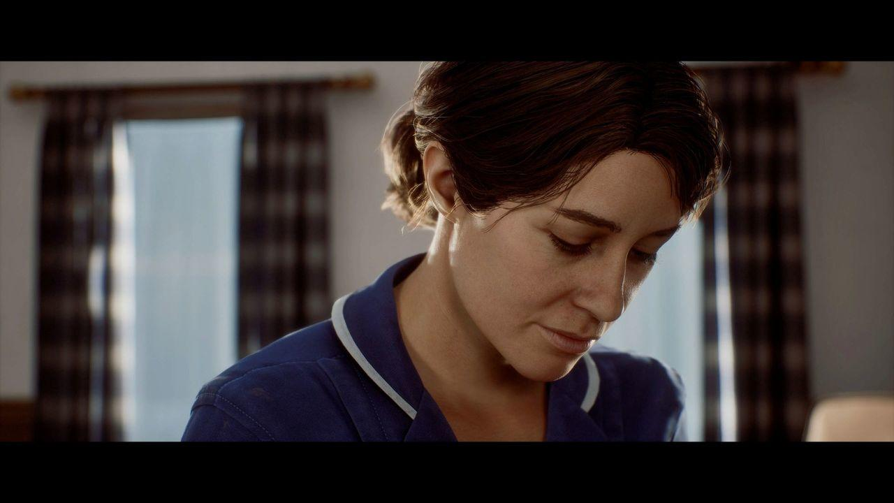 Eine Frau mit braunen Haaren im Dutt trägt ein blaues Oberteil mit weißem Kragen.