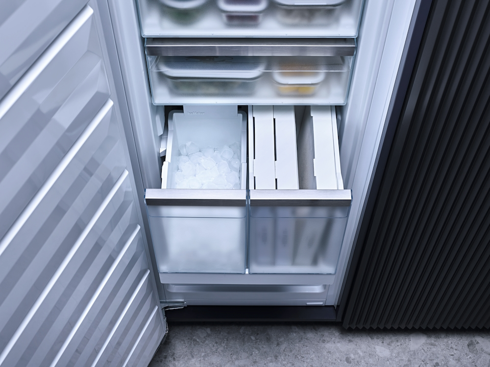 Offener Kühlschrank mit Eiswürfelbehälter, Schubladen und Lebensmitteln.