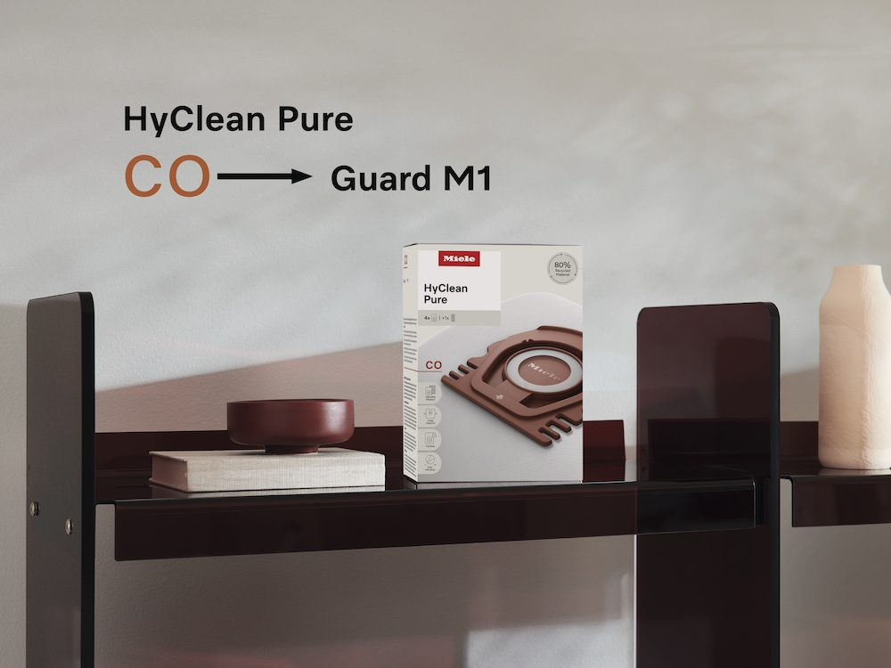 Miele HyClean Pure Staubsaugerbeutel-Box und eine rote Schale auf einem Regal.