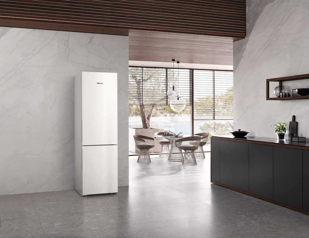 Ein weißer Kühlschrank steht in einer modernen Küche mit Marmorwänden.