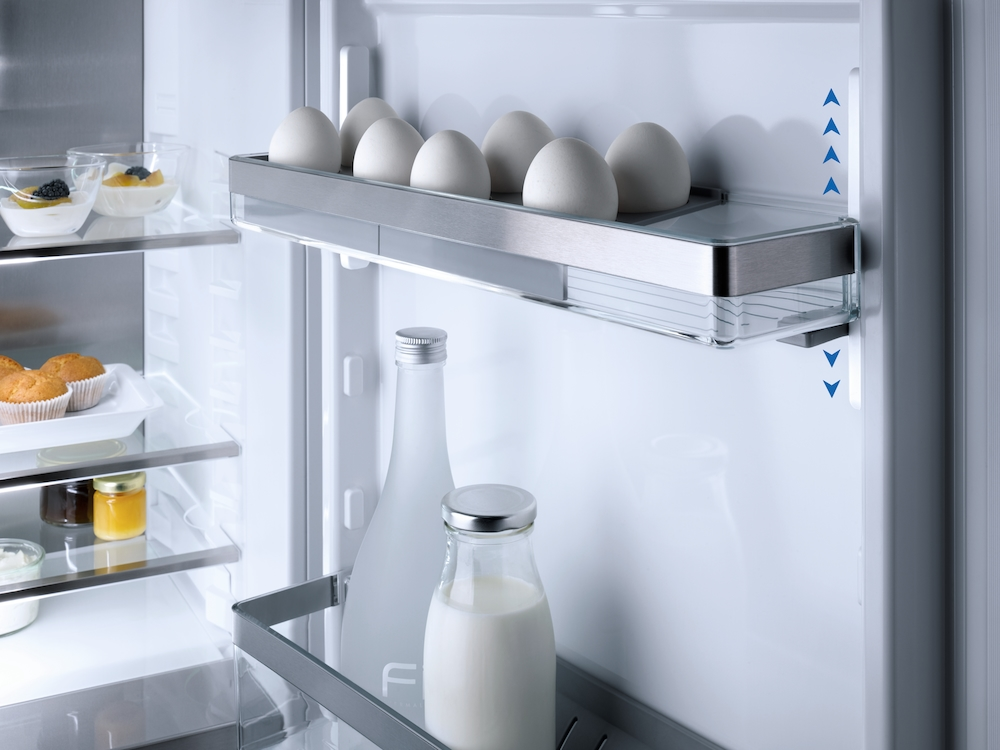 Kühlschrank-Innenraum mit Eiern, Milch, Joghurt, Muffins und Marmelade.