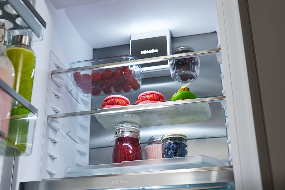 Ein offener Kühlschrank mit Lebensmitteln: Beeren, Kuchen und Marmelade.