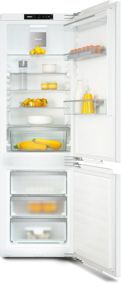 Offener Kühlschrank mit Eiern, Milch, Saft, Zucchini und Zitronen.