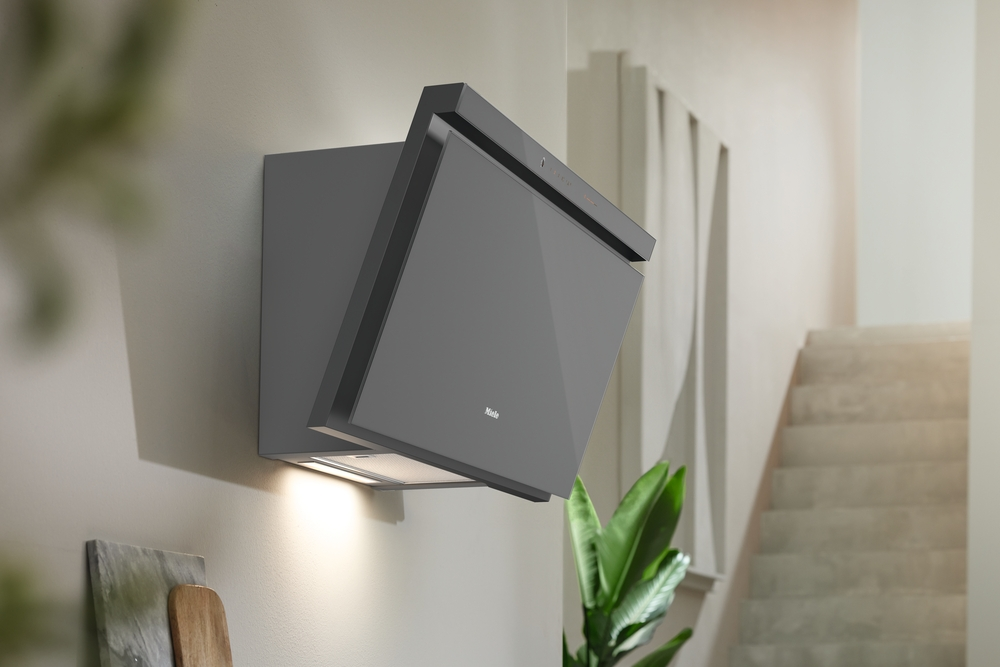 Grauer Dunstabzugshaube mit Glasfront an einer Wand, beleuchtet.