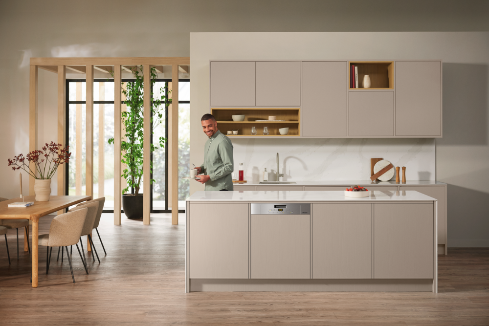 Mann in heller Küche mit Essbereich und offenem Holzelement.