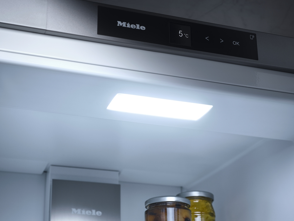 Innenraum eines Miele-Kühlschranks mit beleuchtetem Panel und zwei Gläsern.