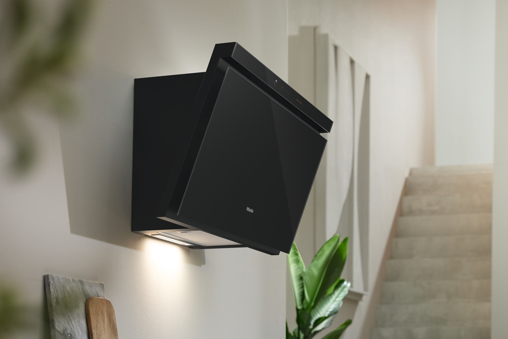 Schwarze Dunstabzugshaube an einer Wand montiert, mit Beleuchtung und Pflanzen.