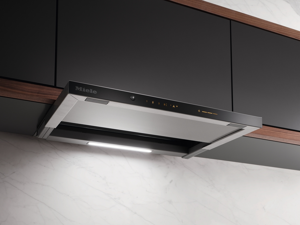 Eine Miele Dunstabzugshaube aus Edelstahl und Glas über Marmorarbeitsplatte.