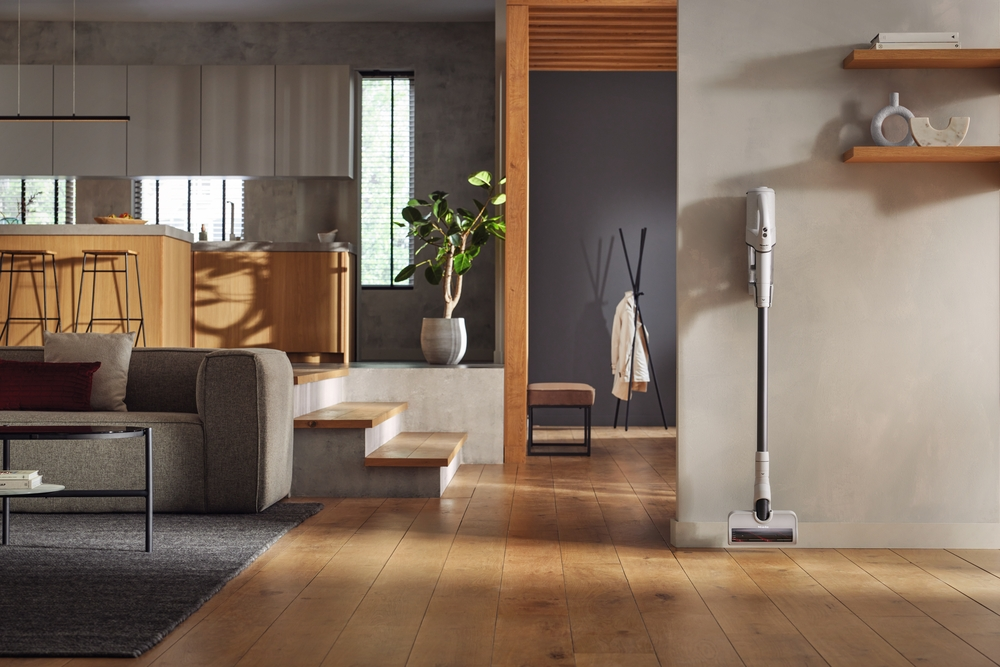 Modernes Wohnzimmer mit Küche, Sofa, Staubsauger und Pflanzen.
