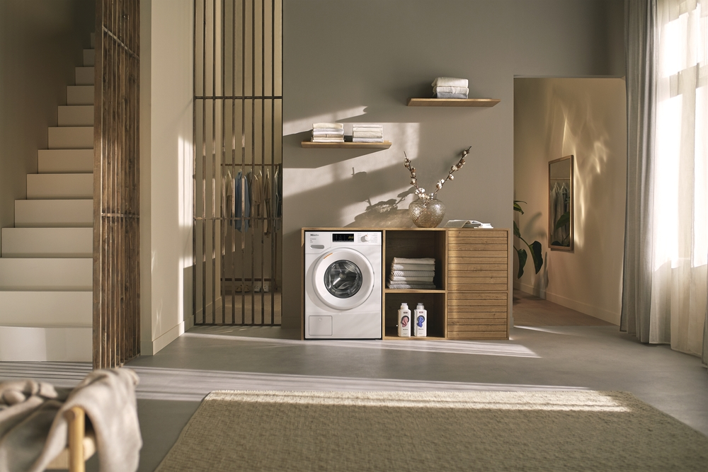 Waschküche mit Waschmaschine, Holzschrank, Treppe und Kleiderständer.