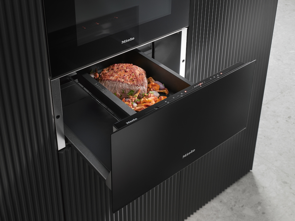 Eine Miele Wärmeschublade zeigt einen Rinderbraten mit Gemüse. Die Schublade ist offen.