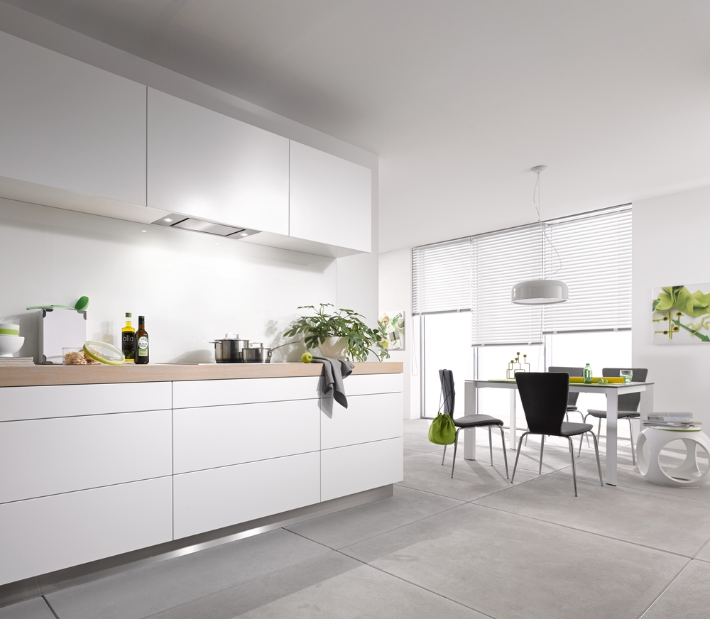 Moderne weiße Küche mit Essbereich, Holzarbeitsplatte, Töpfen und Pflanzen.