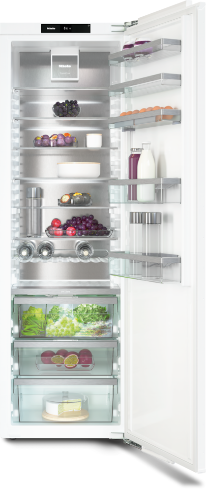 Ein offener Kühlschrank mit Früchten, Eiern und Käse auf den Regalen.