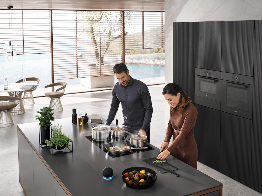 Paar kocht in einer modernen Küche mit Kochinsel und Meerblick.