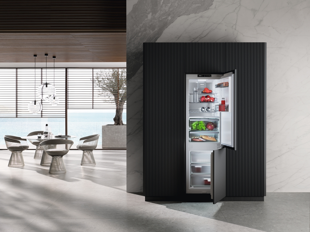 Ein offener Kühlschrank mit Lebensmitteln neben einem Essbereich mit Blick aufs Meer.