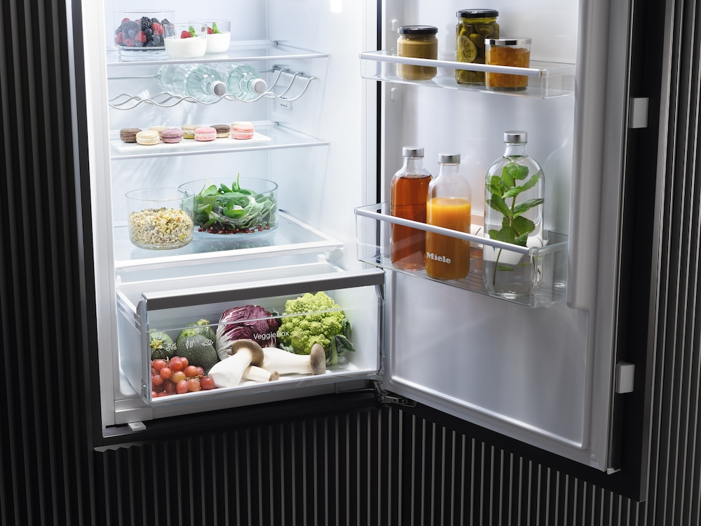 Ein offener Kühlschrank mit Lebensmitteln: Beeren, Macarons, Gemüse und Getränke.