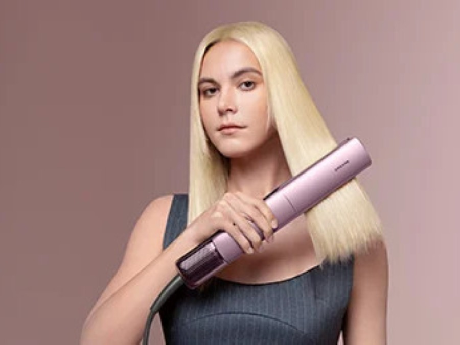 Kobieta z blond włosami używa różowej prostownicy.