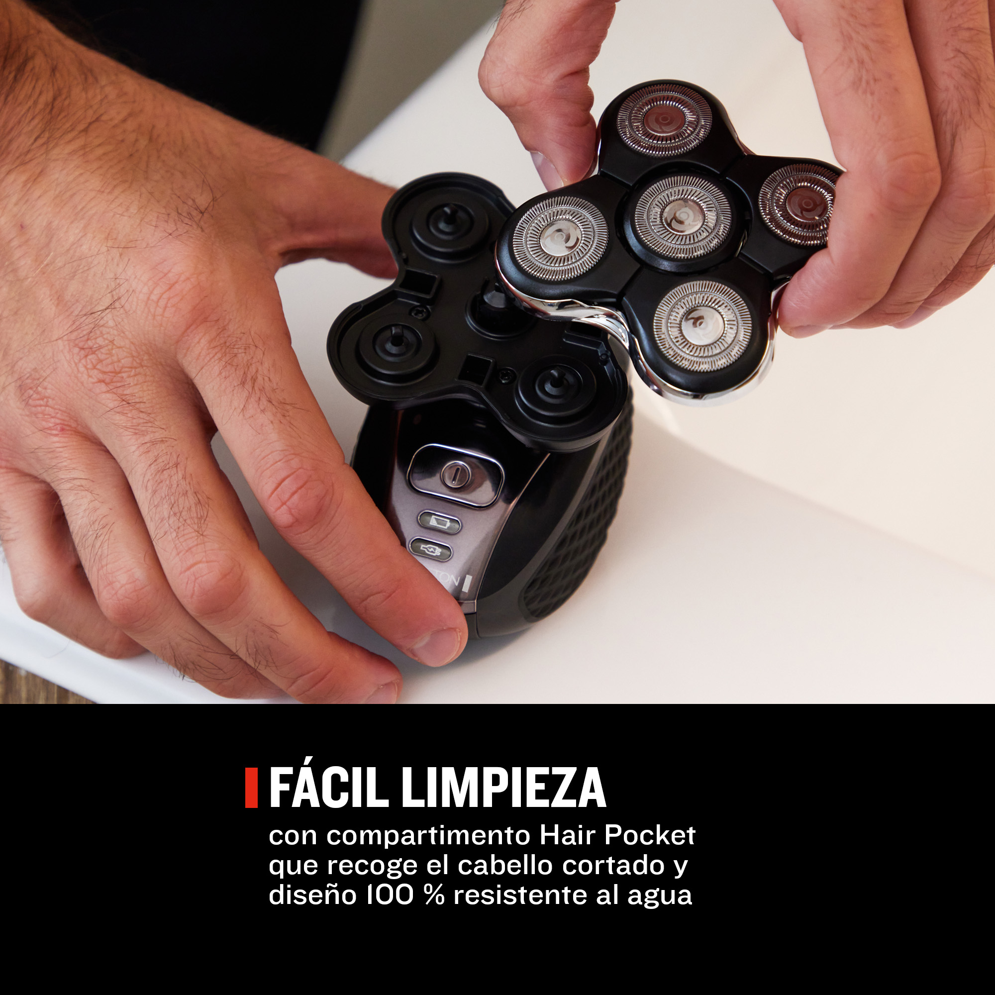 Hombre limpiando una afeitadora negra con cabezales, diseño 100% impermeable.