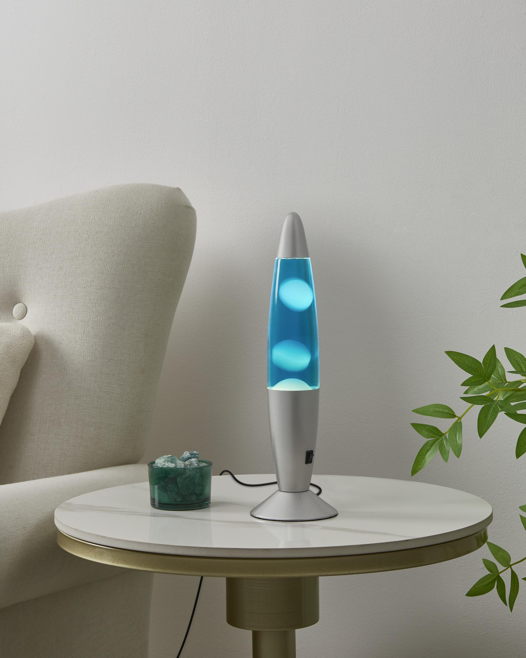 Ein silberner Lava-Lampen-Ständer mit blauem Inhalt auf einem runden Tisch.