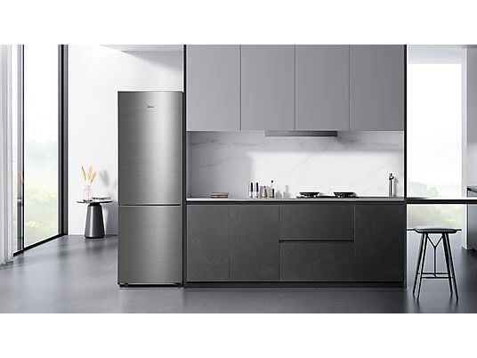 Cocina moderna con nevera plateada, armarios oscuros y salpicadero de mármol.