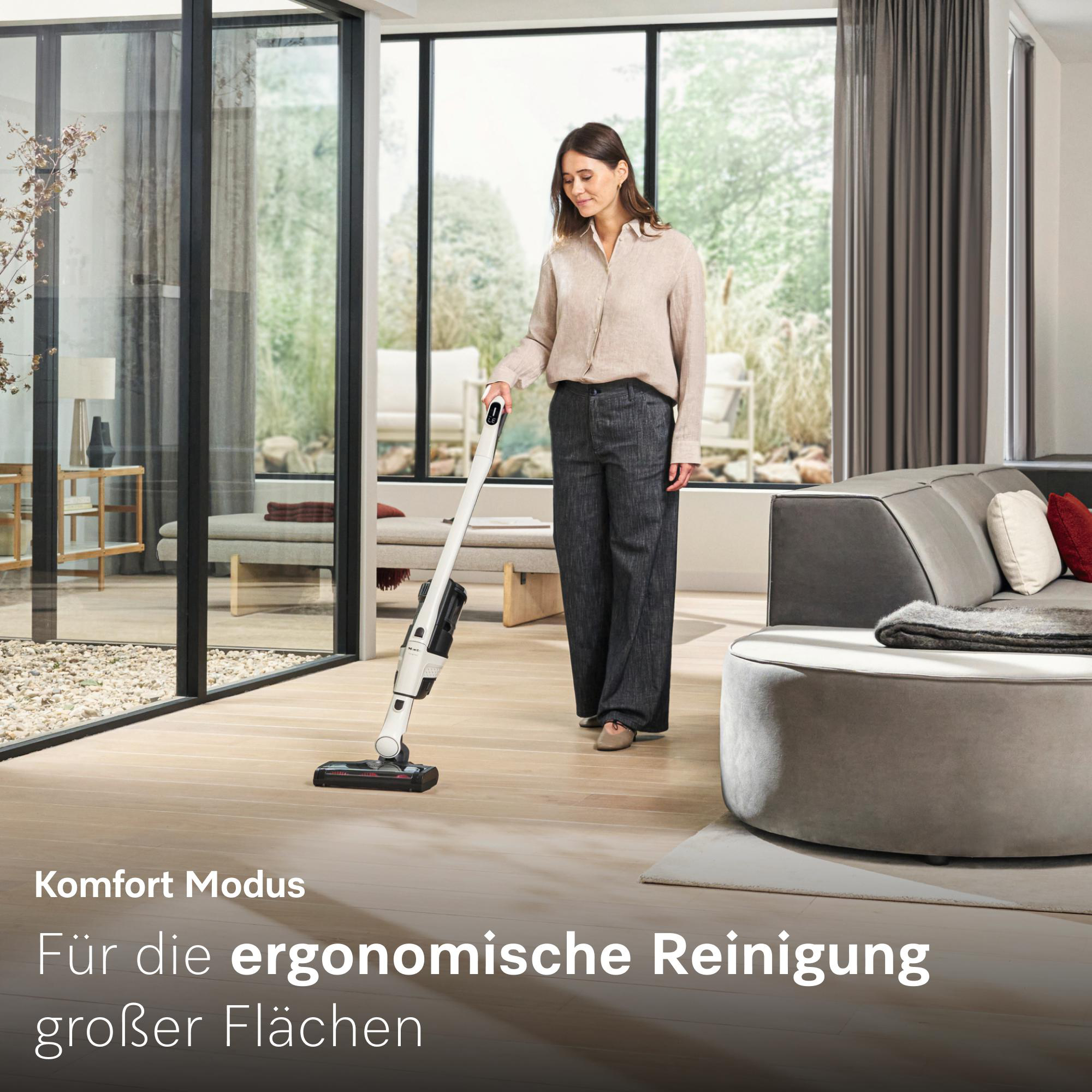 Eine Frau saugt mit einem weißen Staubsauger in einem hellen Raum.
