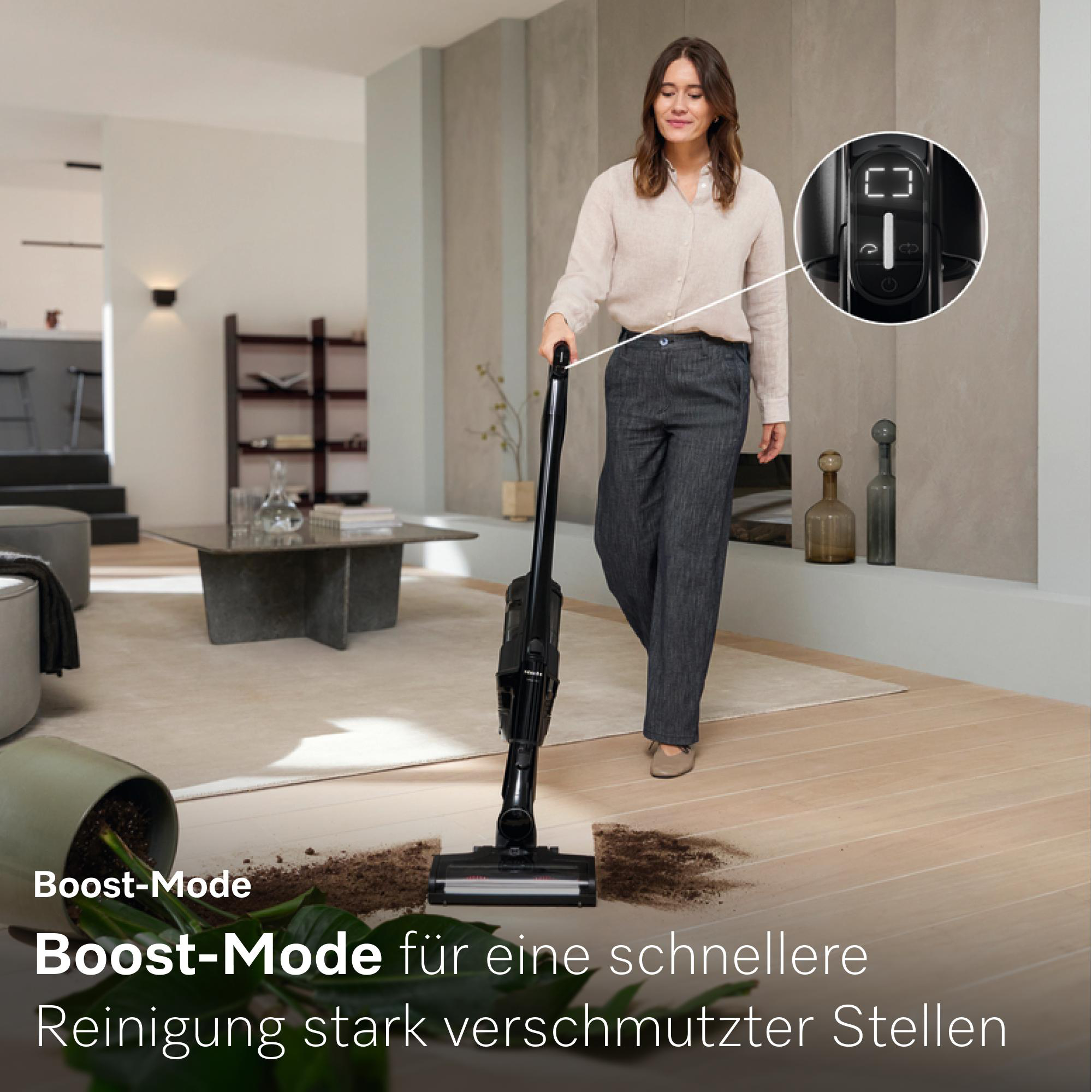 Frau saugt verschüttete Erde mit einem Akkusauger auf. Der Boost-Modus ist aktiviert.