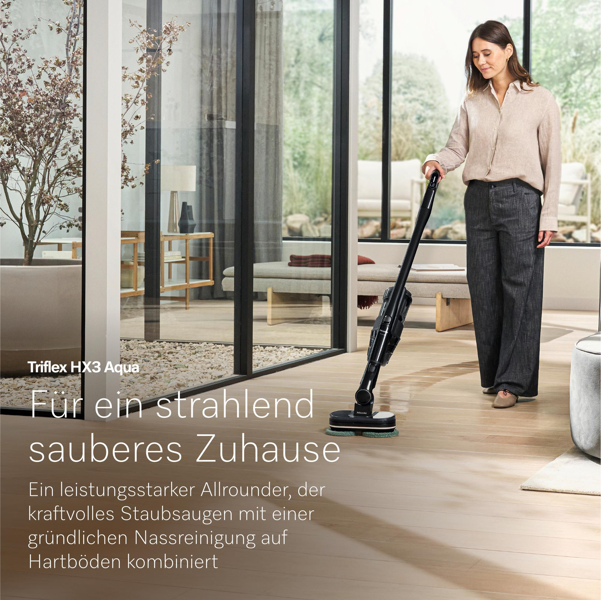 Eine Frau saugt mit einem Miele Triflex HX3 Aqua Staubsauger auf einem Holzboden.