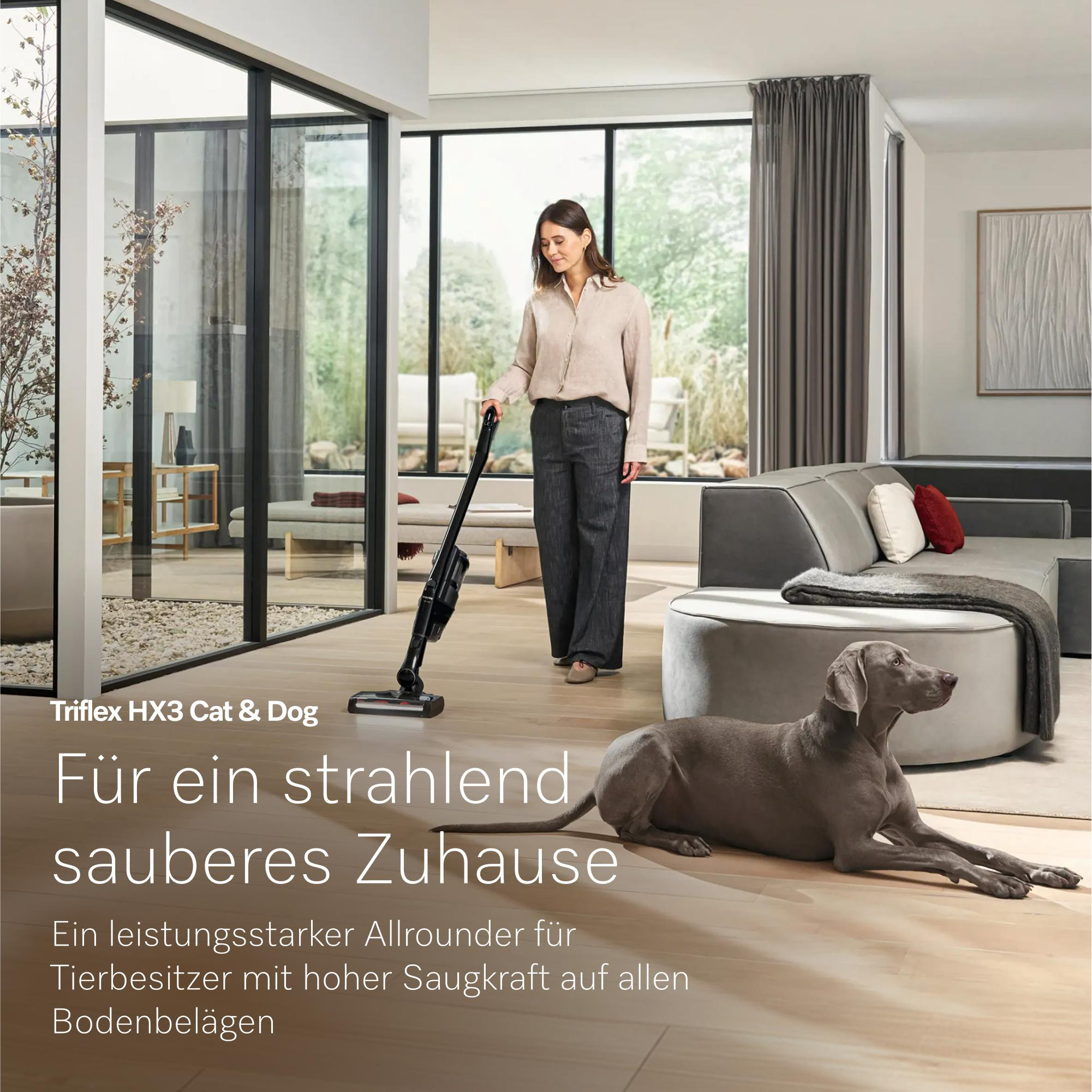 Eine Frau saugt im Wohnzimmer, während ein Hund auf dem Boden liegt.