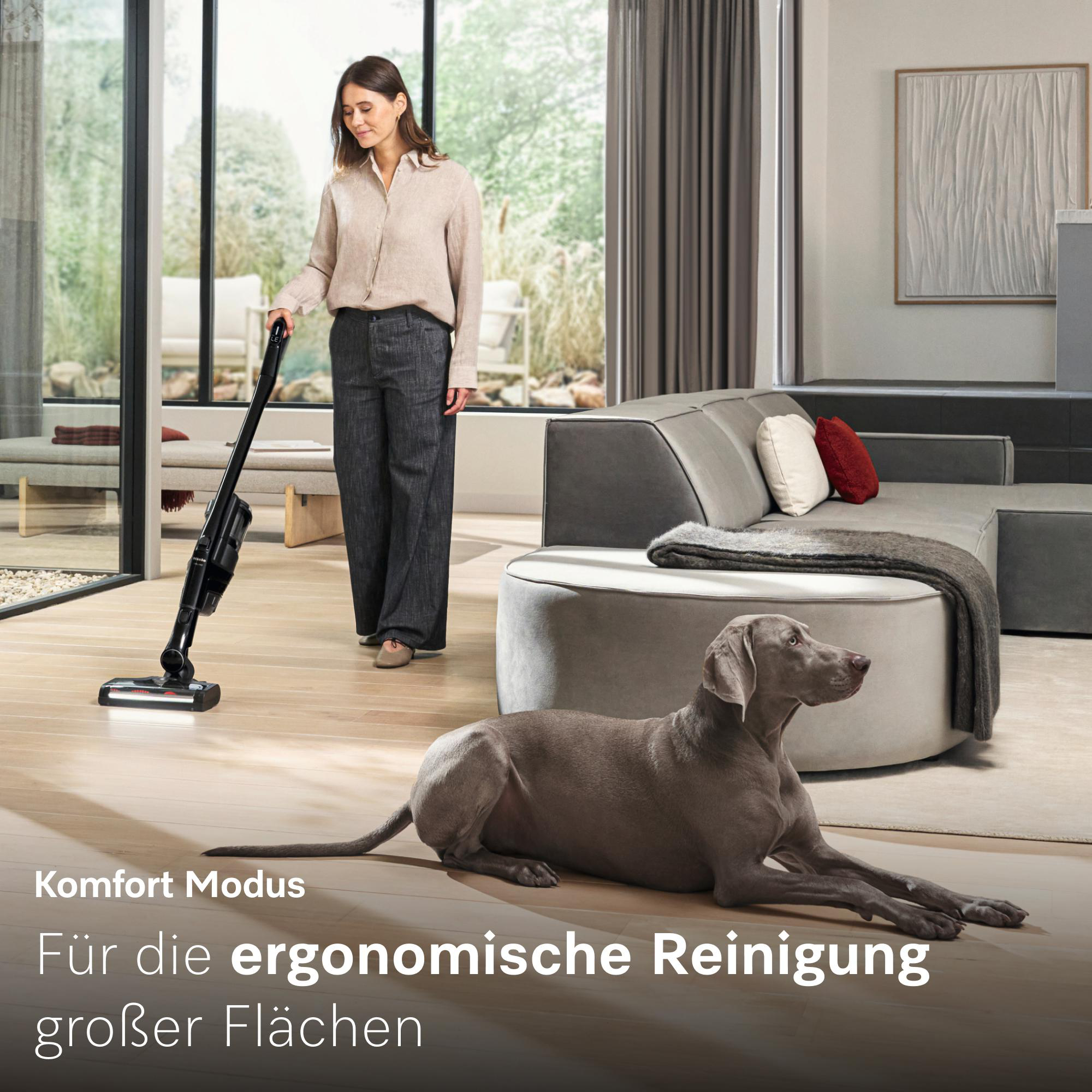 Frau saugt in einem modernen Wohnzimmer mit einem Hund am Boden.