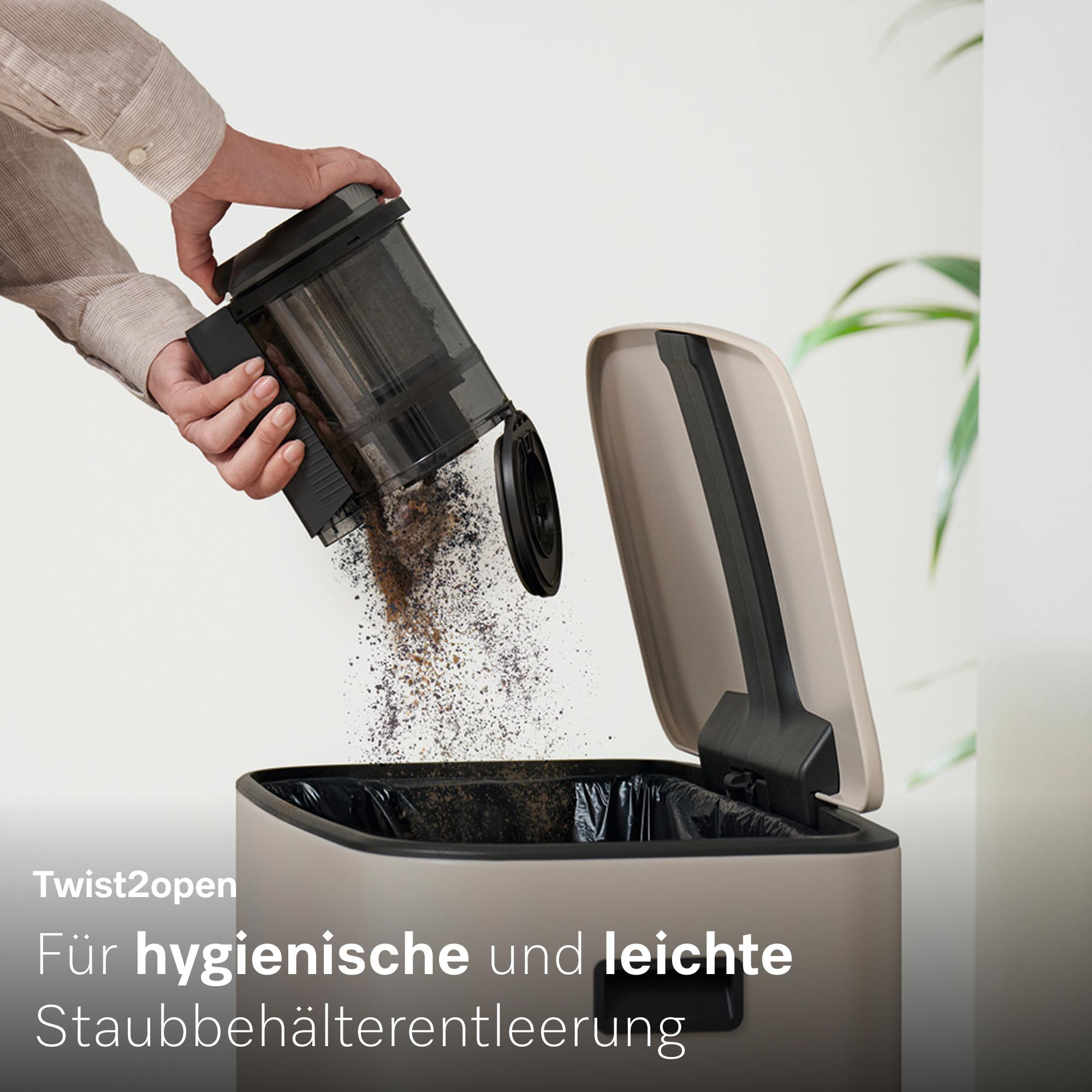 Eine Hand leert Staub aus einem Behälter in einen Mülleimer.