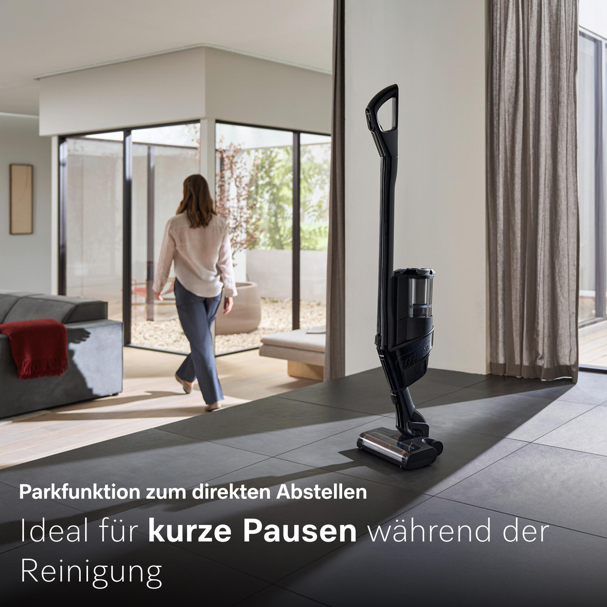 Ein schwarzer Akku-Staubsauger steht auf einem grauen Fliesenboden.
